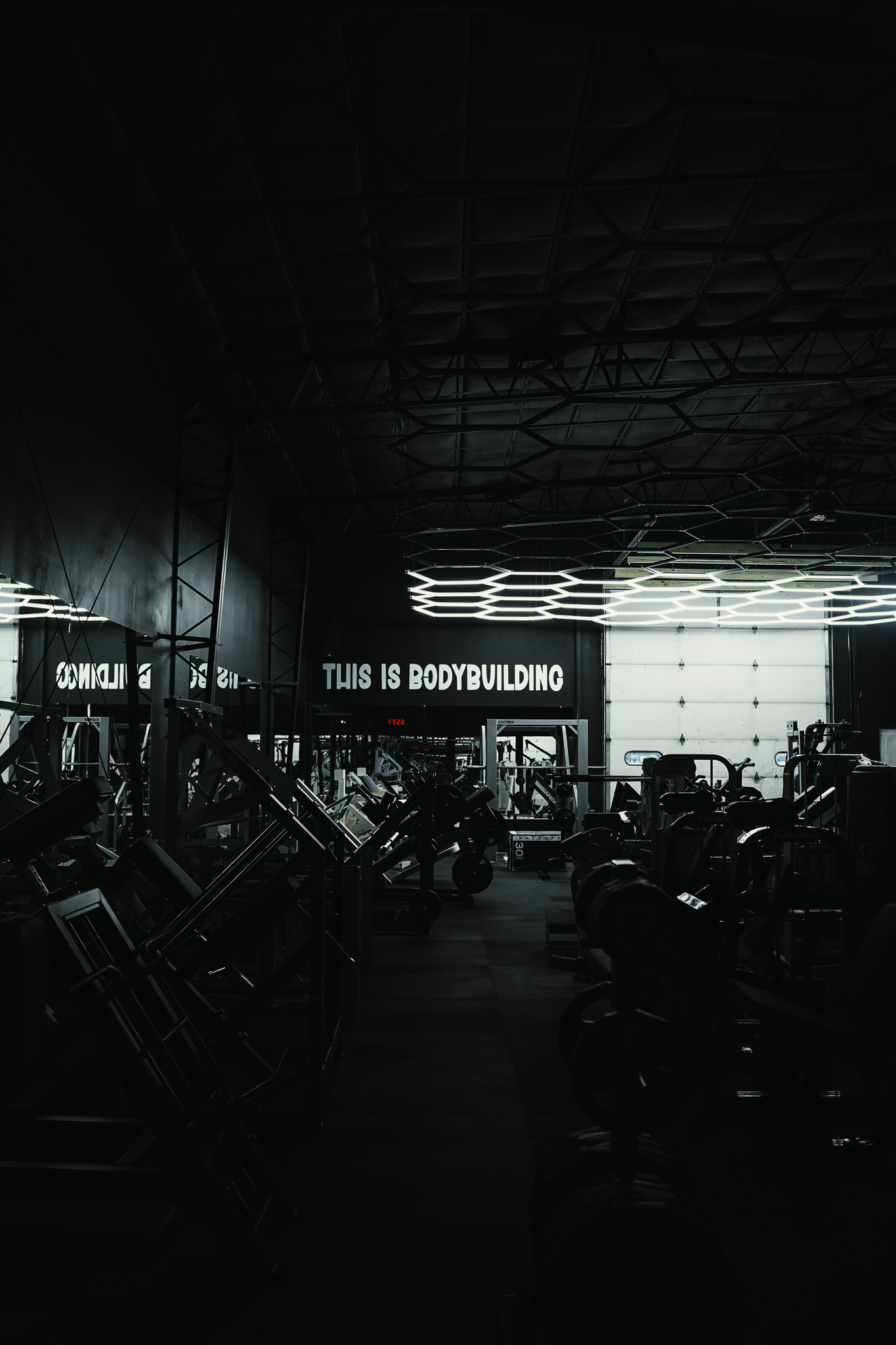 A dark bodybuilding gym floor beneath geometric lighting