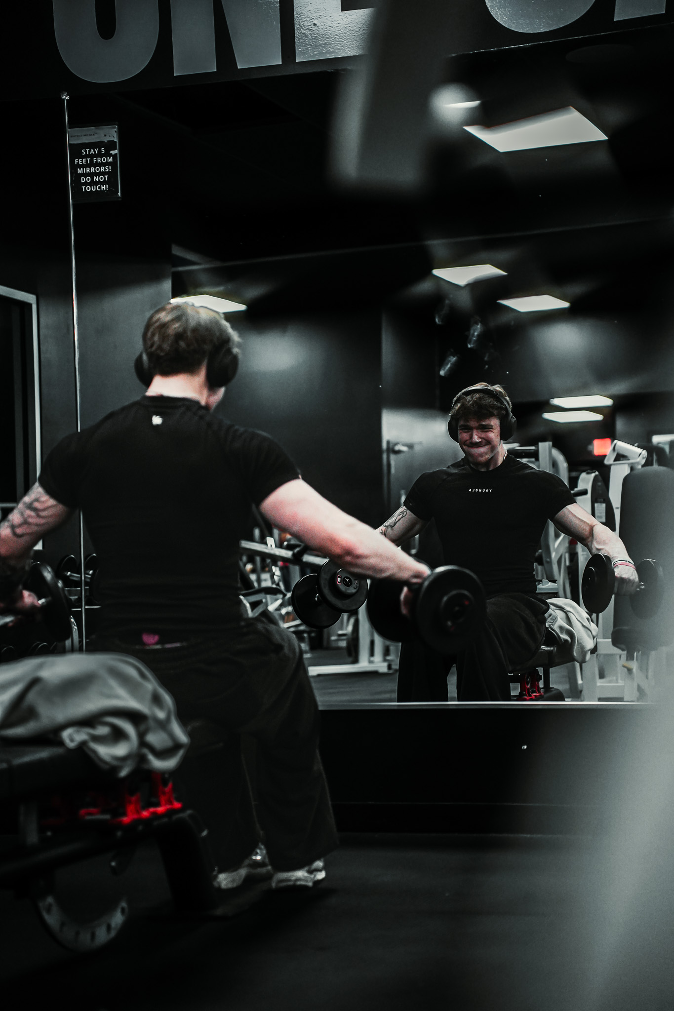 Athlete training with dumbbells in a gym mirror
