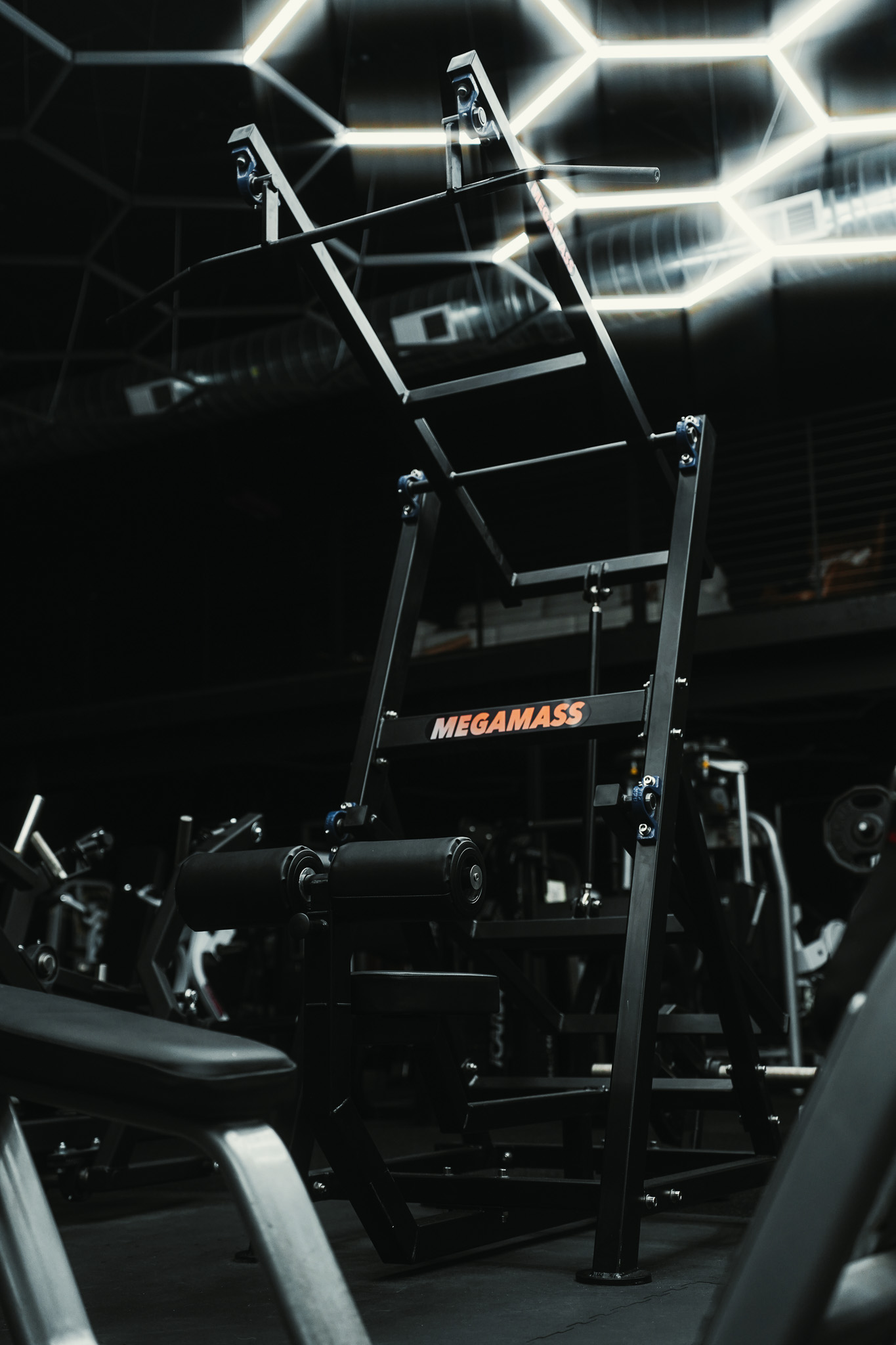 Megamass gym machine beneath geometric lights