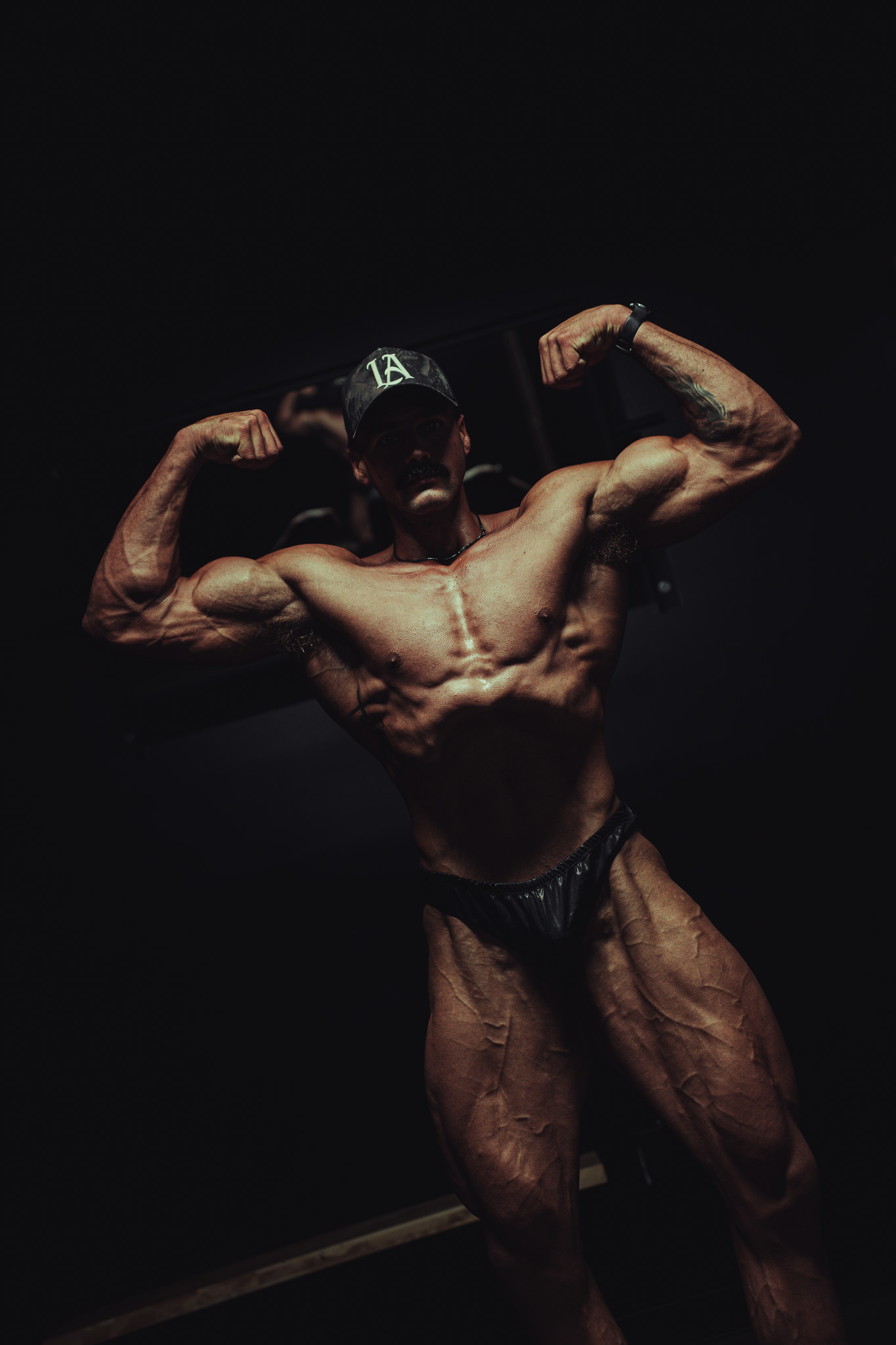 Bodybuilder posing under dramatic gym lighting